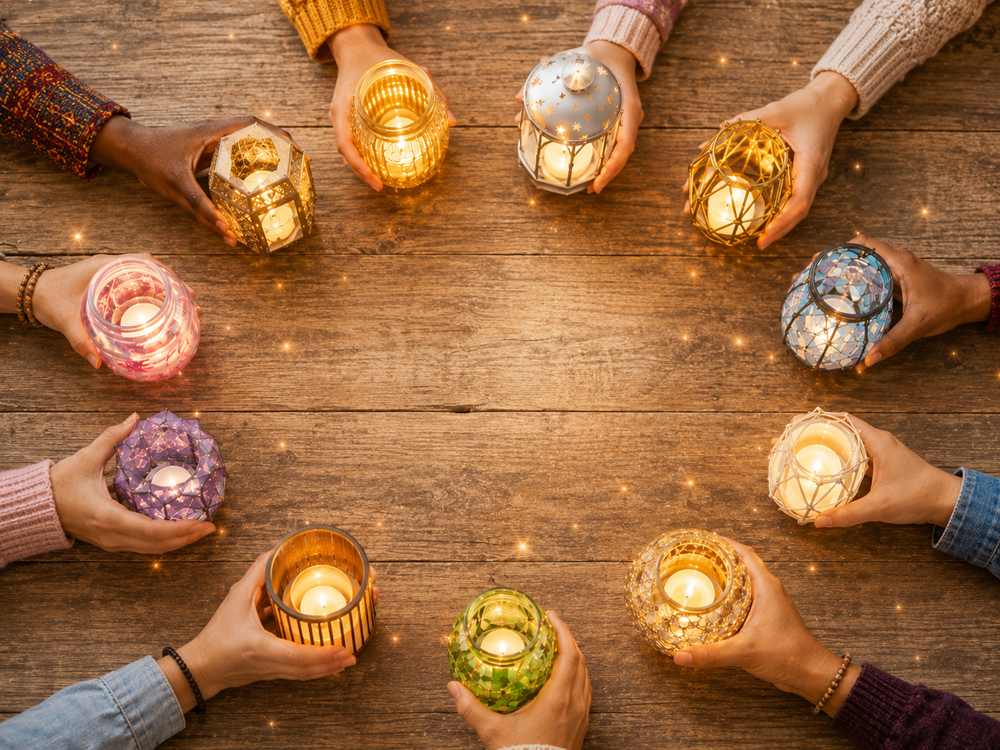 Diverse group of people holding glowing candles together in a circle, representing individual spiritual gifts, community, and honoring each person’s unique path.
