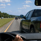 Driver on a freeway noticing an intuitive warning while another vehicle begins merging into their lane, representing Energy Hygiene, personal frequency, and intuitive awareness.